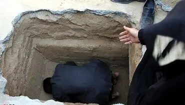 عکس/ نماز خواندن یک پدر در قبر فرزندش
