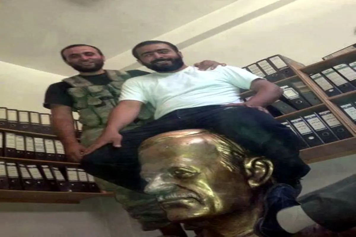 عکس یادگاری مخالفان مسلح با مجسمه حافظ الأسد بعد از تصرف گذرگاه مرزی